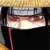 Pixelated static image of a person's face with red eyes and dark hair, set against a light background with vertical pink streaks.