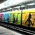 A colorful train with a walking figure on its side, viewed from above in a of four showing slight variations