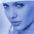 Pixelated close-up of a person's face with blue-toned skin, green eyes, and a faint smile, set against a light blue background.