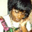 Pixelated image of a person with dark hair wearing a white shirt and green accents, raising a pink and brown object against a light background.