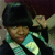 Pixelated figure in dark tricorn hat and teal coat with white trim, holding a light-colored object near the face.