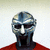 Pixelated figure wearing a metallic helmet with horizontal stripes and a red garment against a light gradient background.
