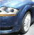 A pixelated close-up of a blue vehicle's front section showing headlight, grille, and wheel details.
