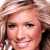 Pixelated close-up of a smiling person with light brown hair and fair skin, cropped to show face and upper shoulders.