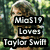 A pixelated image of a woman with long wavy hair in an outdoor setting, overlaid with bold text reading "MioS19 Loves Taylor Swift".