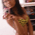 A woman with long dark hair in a yellow bikini top poses against a blurred background, her right hand near her face.