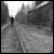 Black-and-white animated scene of a lone figure walking down a narrow, tree-lined path toward a bright light, with pixelated text appearing sequentially.