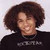 Pixelated image of a person with dark curly hair wearing a black top against light background.