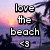 Pixelated text 'love the beach <3' overlaid on a sunset beach scene with palm trees and water.