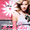 A static image shows a woman in a white dress with a blue and green floral accessory, overlaid with a pink and white flower graphic and text.