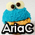 A blue, textured, cookie-like character with large white eyes and brown pupils appears above the text 'AriaC' in various colors.