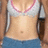 A pixelated close-up of a person's torso wearing a white tank top with pink trim and blue shorts, holding a dark cylindrical object.