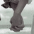 Pixelated grayscale image of a stylized figure with dark hair and a rounded body, standing against a light background.