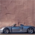 Pixelated image of a blue convertible car with two figures, one driving and one in the passenger seat, against a gradient sky background.