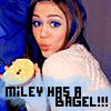 A person with long dark hair and blue eyes holds a bagel in their right hand, wearing a white top against a blue and gray background with text overlay.