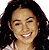 Pixelated static image of a person with long dark hair, light skin tone, and visible facial features including eyes, nose, mouth, and teeth in a smiling expression.
