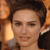 A pixelated close-up of a person with short dark hair, light skin, and a neutral expression against a warm-toned background.