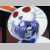 Pixelated circular icon with blue and white patterned design, red circular accents, and dark background elements.