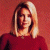 Static image of a person with shoulder-length blonde hair wearing a red top against a reddish-brown background, next to green text reading 'Original Icons .com' on dark green.