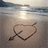 A beach scene with a heart and arrow drawn in sand, paired with text about friendship and sisterhood.