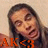 Pixelated image of a person with long dark hair wearing an orange bow tie, set against a light beige background.