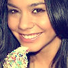 A close-up of a person with long dark hair holding a colorful sprinkle-covered dessert near their mouth.