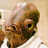 Pixelated image of a character with brown skin and a white shirt on the left, next to red pixelated text on a black background reading "It's A Trap!".