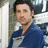 A static pixelated image of a person with short dark hair wearing a blue and white collared shirt against a blurred background.