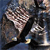 A pixelated figure in dark clothing holds a small object against a dark background with blue and brown tones.