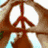 A hand forms a peace sign with a white background, while another hand creates a heart shape around a purple heart symbol.