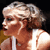 Static pixelated image of a person with light brown hair wearing a white sleeveless top, viewed from the side against a dark background.