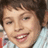 A pixelated image of a smiling child with brown hair on a blue background, with red text elements.