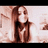 Pixelated static image of a person with long brown hair wearing dark clothing against light background.