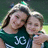 Two people in a green shirt with 'JG' text pose together on the left, while blue background displays green pixelated text reading 'Izzy<33', 'And', and 'Maddie<33'.