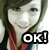 A pixelated image of a person with long brown hair and red highlights wearing a striped shirt, smiling with text "OK!" in bold black letters.