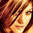 Pixelated close-up of a person's face with brown hair and warm-toned skin, rendered in low-resolution 256x256 pixels.
