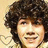 A four-quadrant with a pixelated portrait of a person with curly brown hair on the top-left, pink background with 'Nick Jonas' text top-right, pink background with 'My Love!' text bottom-left, and solid gray bottom-right