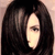 Pixelated close-up of a person with long dark hair, light skin, and closed eyes, set against a neutral background.