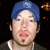 A pixelated image shows a person wearing a blue cap and dark shirt with white trim, next to bold text on a split background.