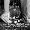 Black-and-white image of a person's lower legs and feet wearing Converse sneakers, with a heart-shaped outline over the shoes.