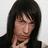 A person with long dark hair and blue eyes in a black sleeveless top, shown in four with subtle facial expression changes