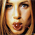 A pixelated close-up of a person's face with light brown hair, showing eyes, nose, mouth, and part of the forehead under warm lighting.