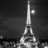 Black-and-white pixelated image of a tall, slender tower with a flagpole and circular light fixture against dark background.