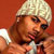 Pixelated static image of a person with light-colored hair wearing dark sunglasses and holding a microphone against an orange background.
