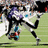 Pixelated figure in dynamic pose with purple hair, white top, black pants, and red shoes on green field background.