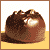 Pixelated brown dessert with white filling on yellow surface, two versions differ by black text above dessert.