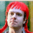 A pixelated image of a person with bright red hair against a green background, overlaid on a solid red field with bold black text.