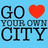 Pixelated graphic with bold black text 'GO YOUR OWN CITY' on light blue background, red heart symbol replacing the word 'LOVE'.
