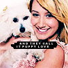 A woman with blonde hair holds a small white dog with black eyes and nose; text overlay reads 'AND THEY CALL IT PUPPY LOVE' in pixelated font.