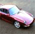 Pixelated static image of a red and white car with blue accents on a gray background, viewed from a low angle.